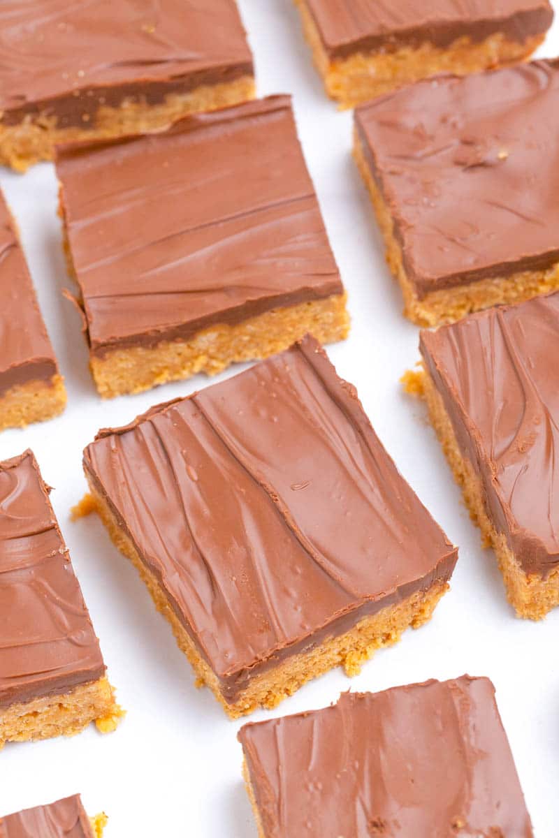 Chocolate covered peanut butter bars cut into squares on white table