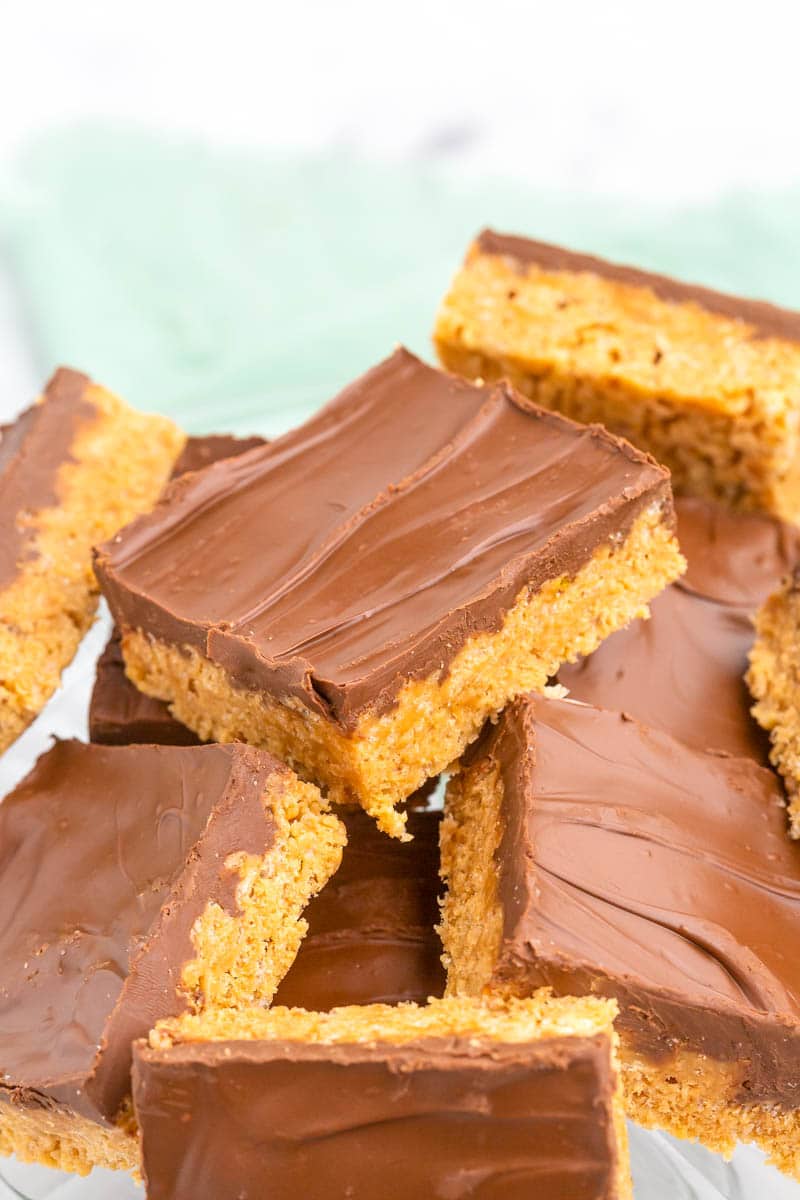 Chocolate covered peanut butter bars cut into squares stacked on top of each other