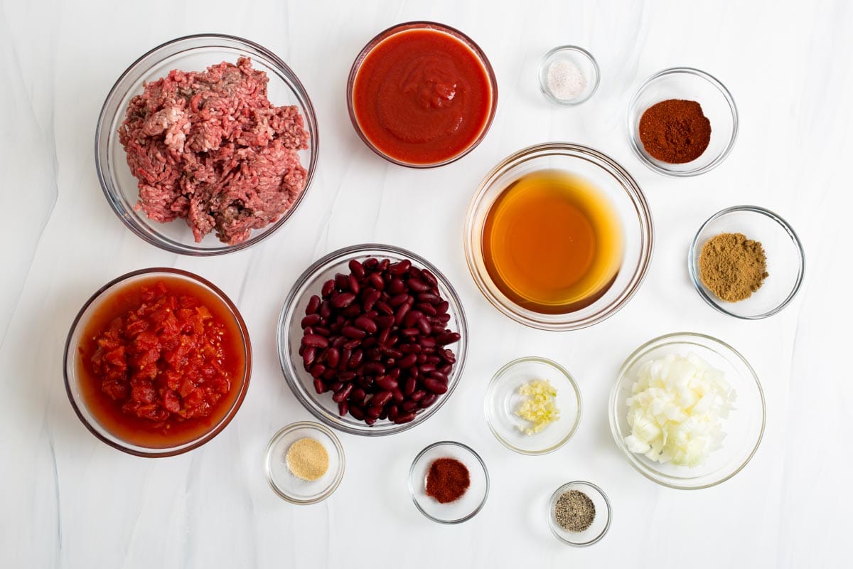  ingredients for crock-pot chili on a white counter in individual glass bowls.