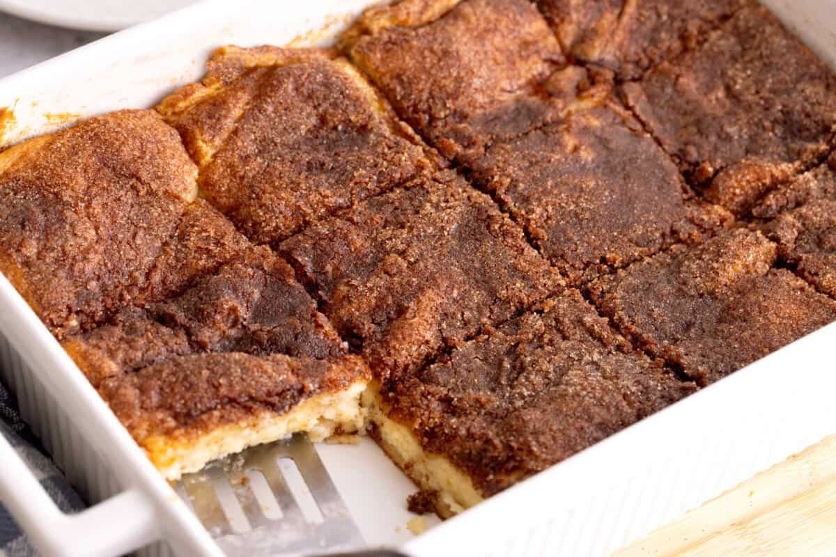 Spatula serving sopapilla cheesecake bar from baking dish.
