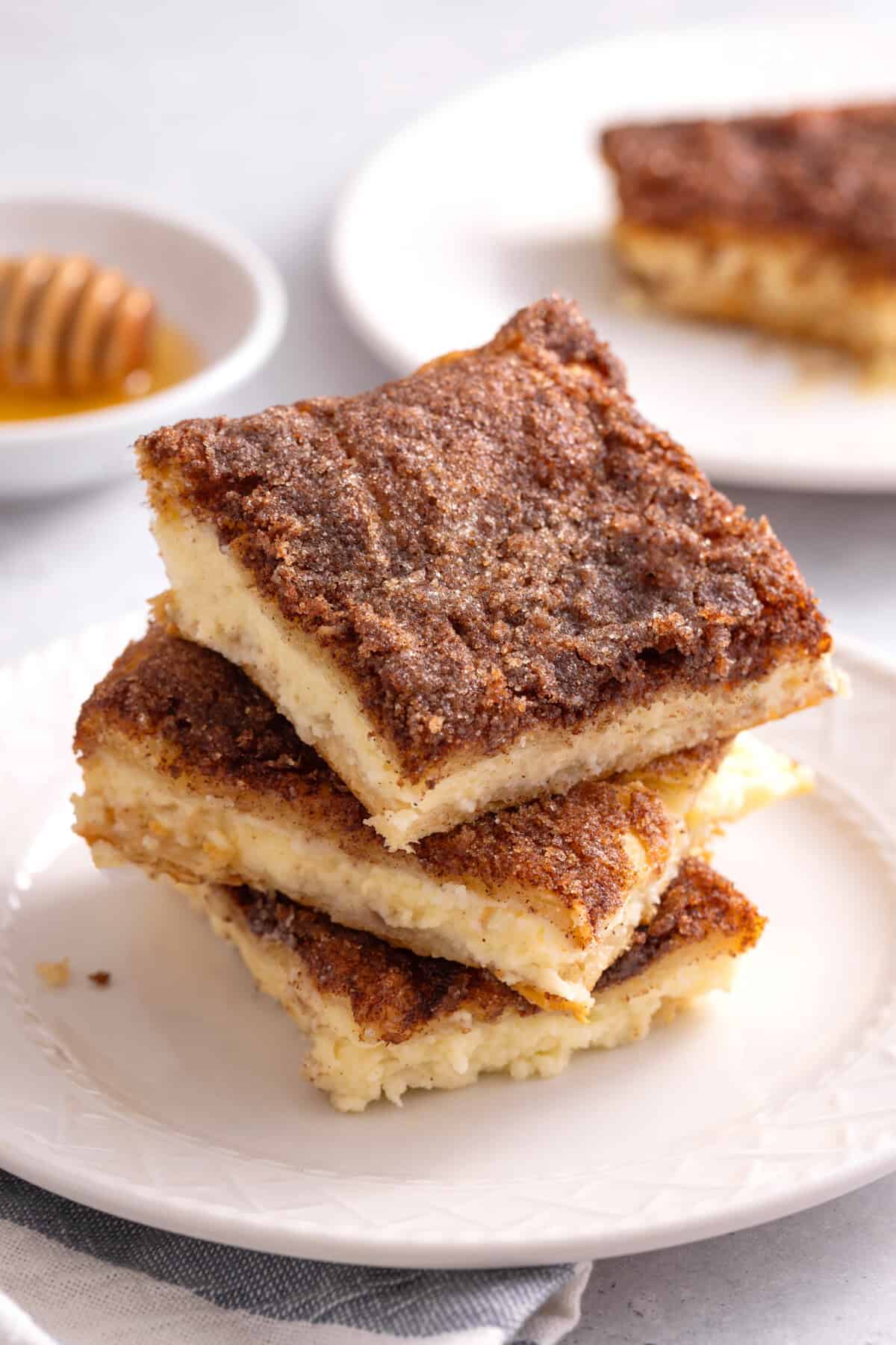 Stack of 3 sopapilla cheesecake bars on plate.