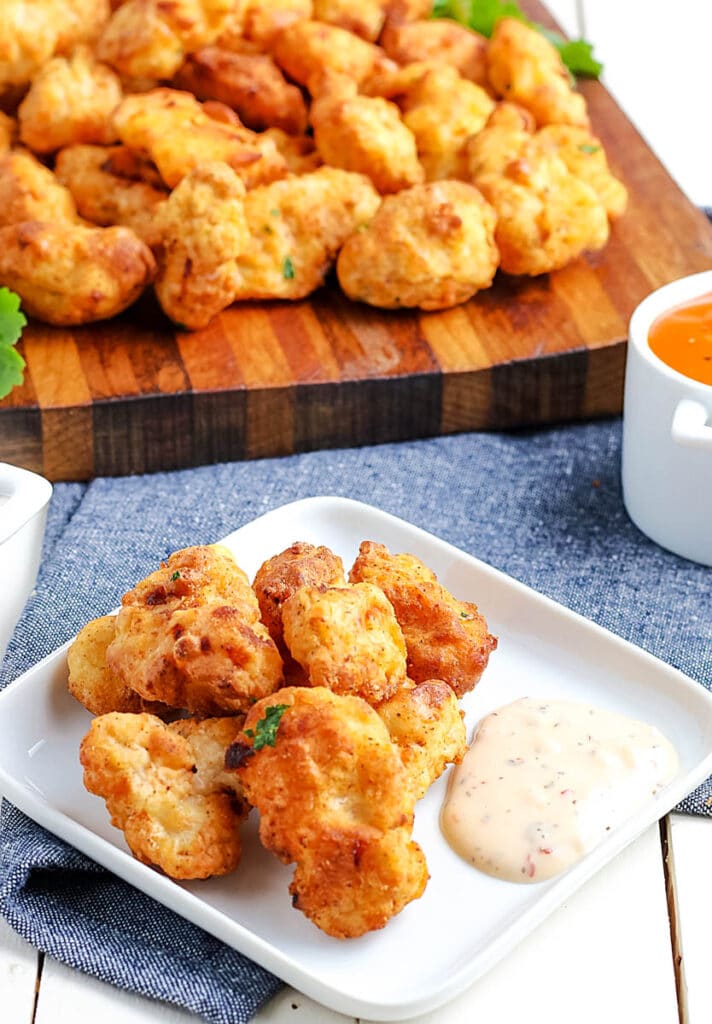 air fryer popcorn chicken bites on a white plate with dipping sauces
