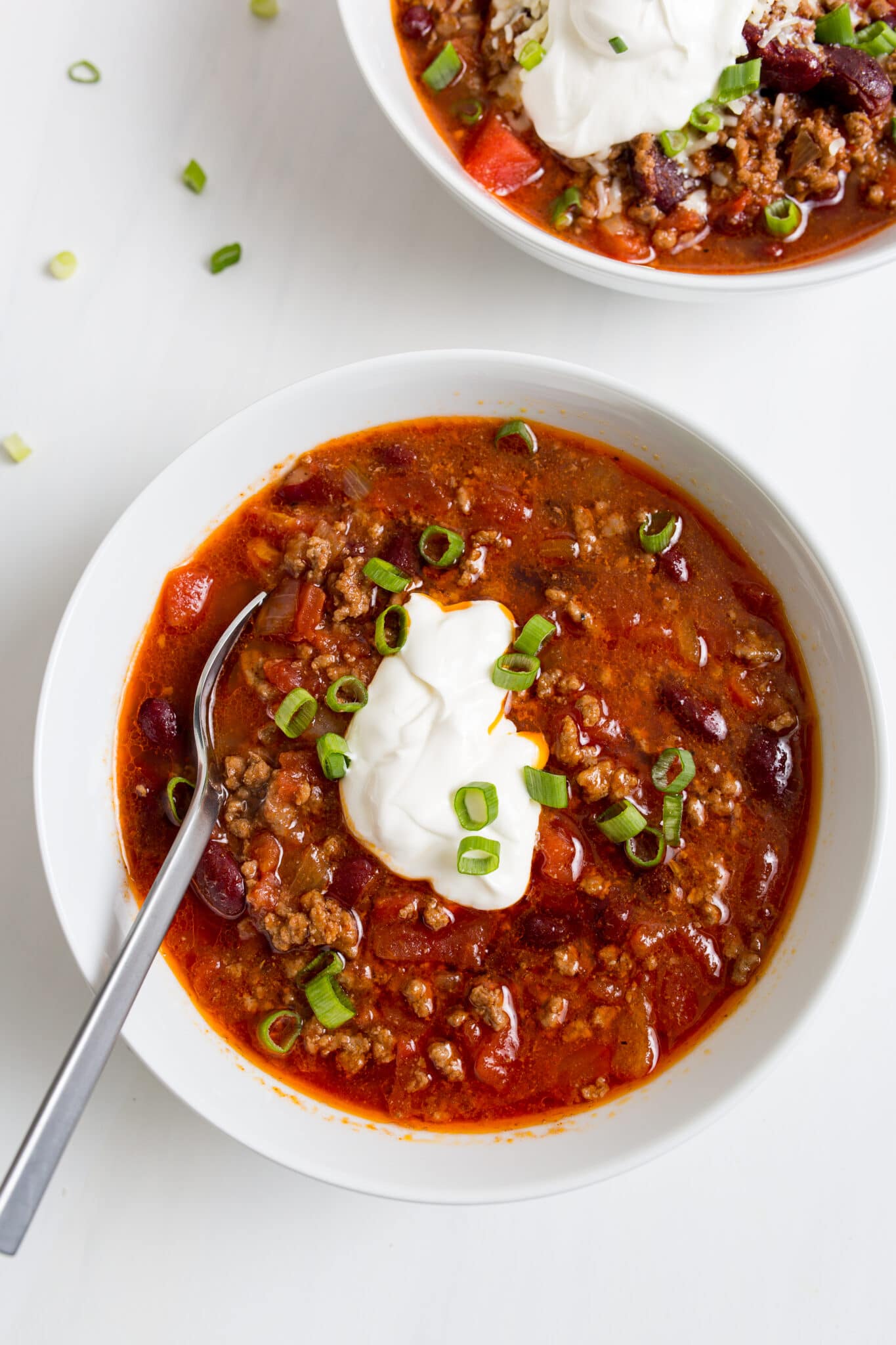 bowl of chili topped with chives and sour cream 