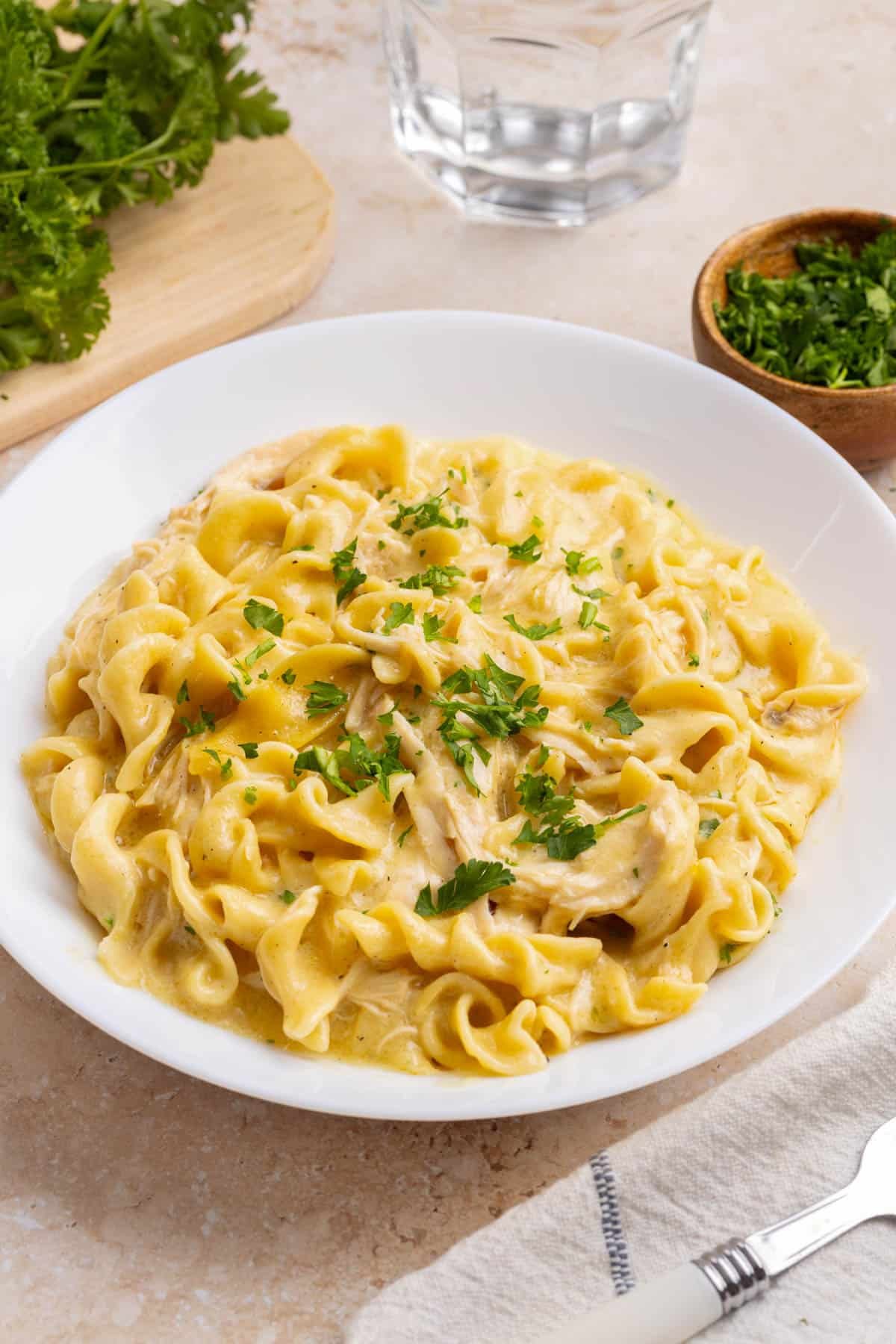 A bowl filled with crockpot chicken and noodles on a countertop for serving.