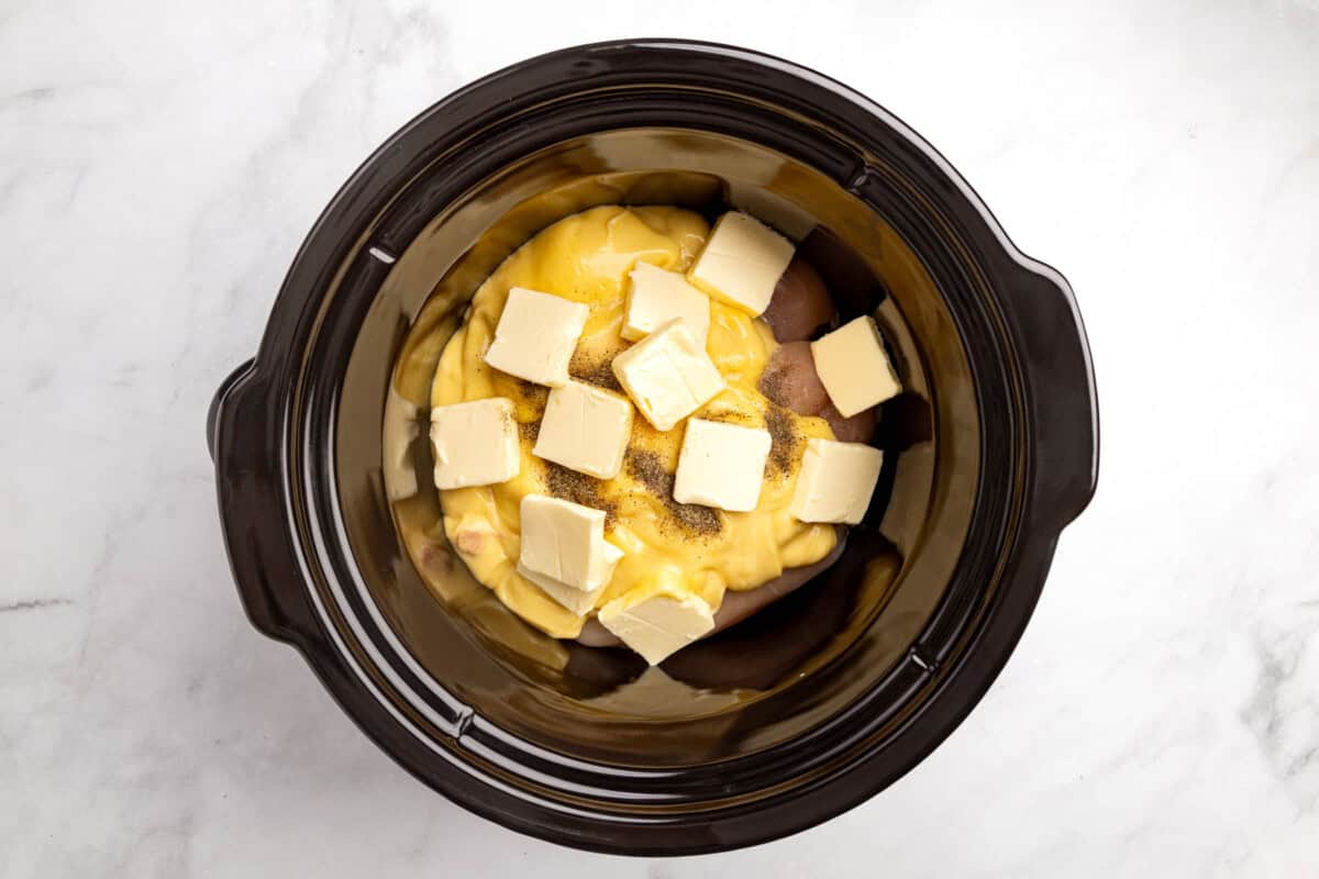 Chicken in the crockpot with the cream of chicken soup and the sliced butter and seasonings on top.