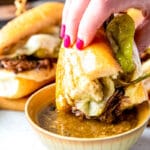 hand holding a mississippi sandwich and dipping it into au jus