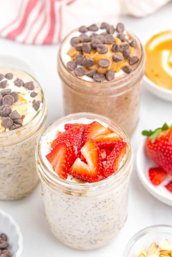 overnight oats with chia seeds in mason jar with spoon, topped with sliced strawberries.