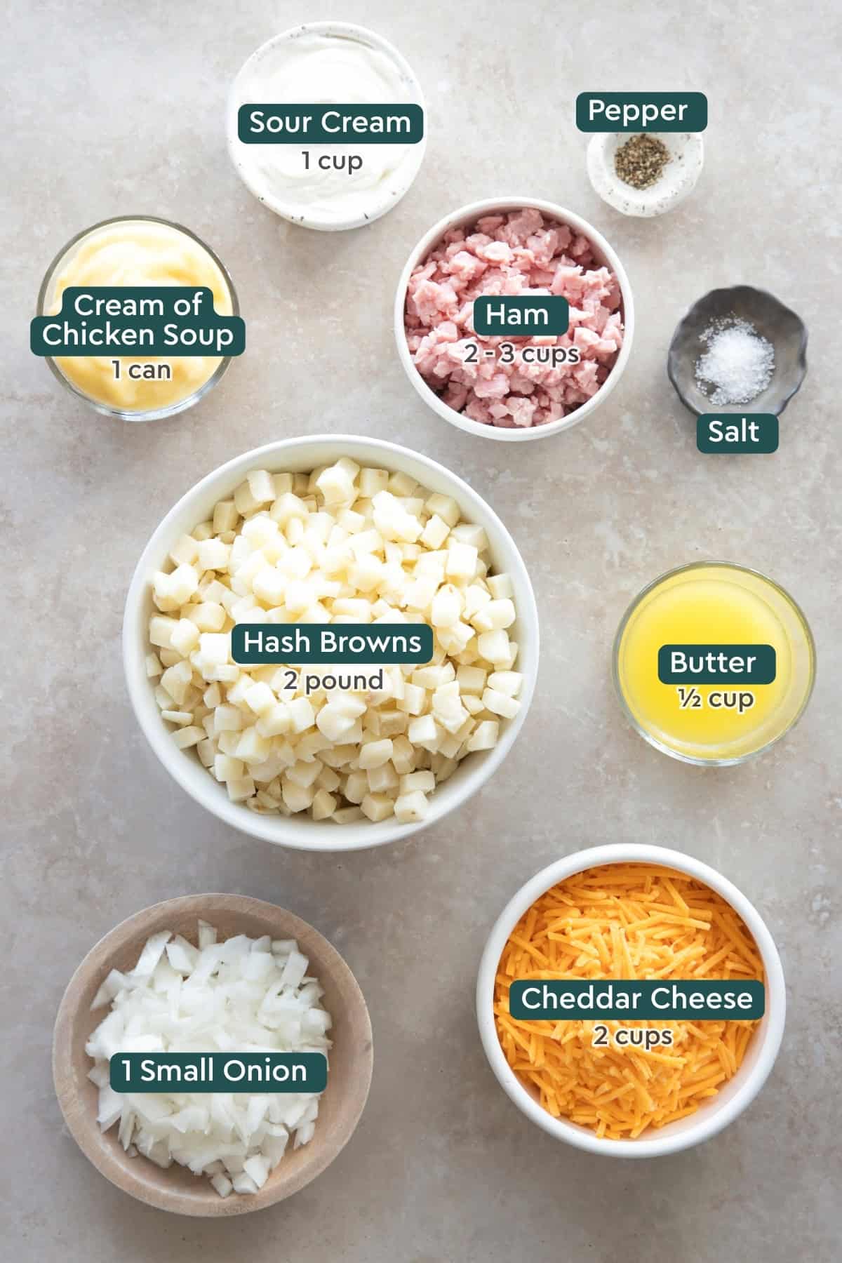 Ingredients for cheesy ham and potato casserole, including sour cream, pepper, salt, ham, cream of chicken soup, hash browns, butter, onion, and cheese.