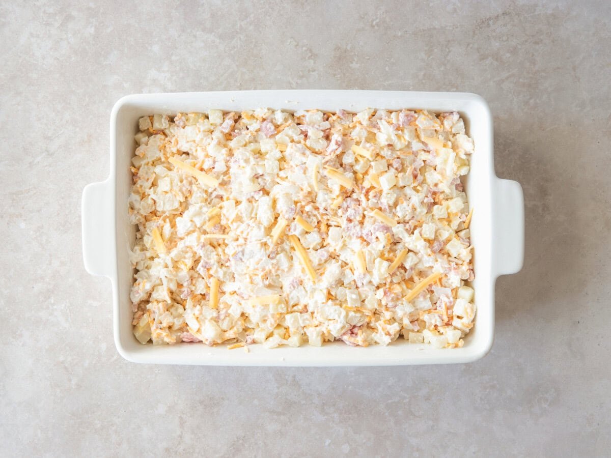 Cheesy ham and potato casserole in dish before baking.
