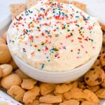 bowl of creamy fruit and cookie dip with animal crackers surrounding it