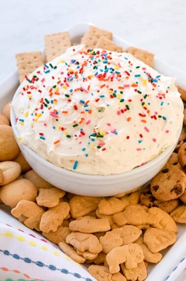 bowl of creamy fruit and cookie dip with animal crackers surrounding it