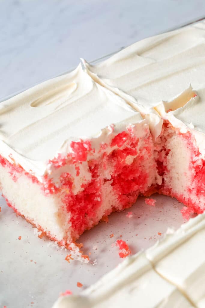 close up of poke cake topped with whipped cream 