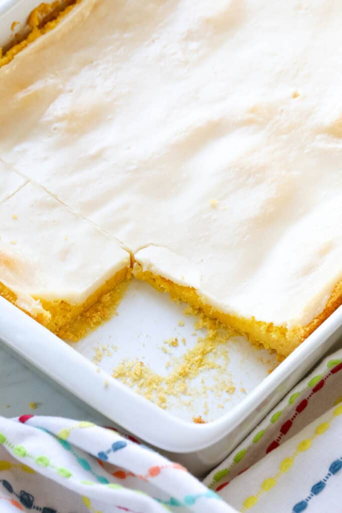 a white baking dished filled with baked lemon bars and 2 bars are removed off screen.