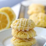 Three cake mix lemon cookies are stacked on top of each other on a white plate.