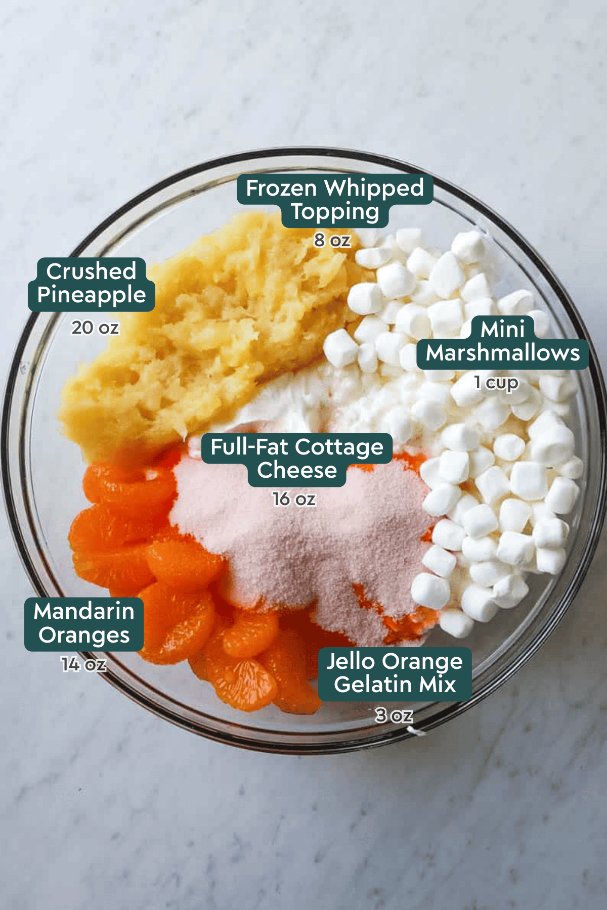 Ingredients needed to make orange fluff salad all inside a glass mixing bowl.