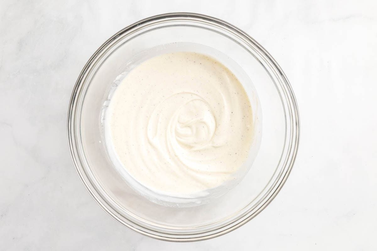The dressing for the salad in a glass bowl on a white countertop.