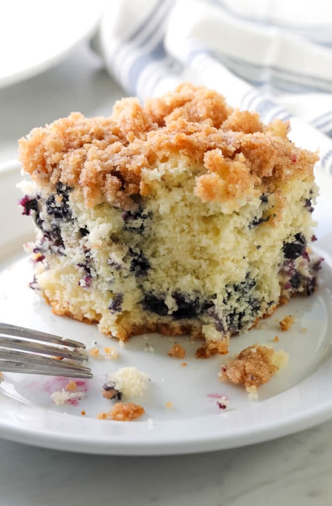 blueberry buckle on a white plate with a bite taken out