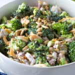 broccoli salad with dressing, cheese, and bacon bits in a white bowl.