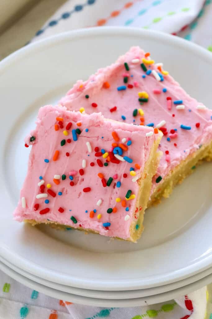 a plate with 2 sugar cookie bars with pink frosting and sprinkles