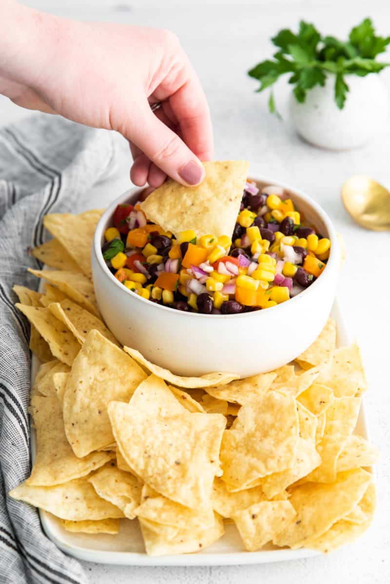 Tortilla chip being dipped into Black Bean and Corn Salsa