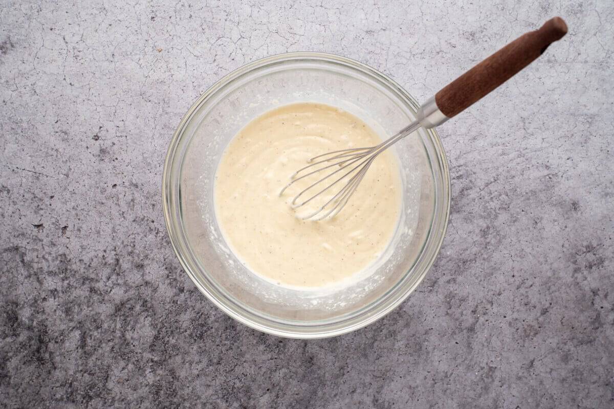 Broccoli salad dressing in bowl with whisk.
