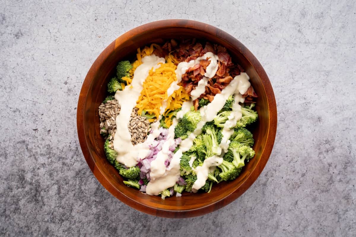 Dressing added to ingredients for broccoli salad.