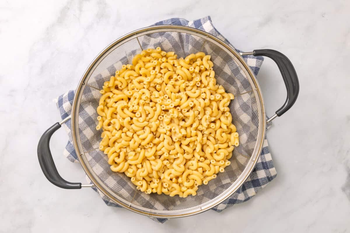 Cooked macaroni in colander.