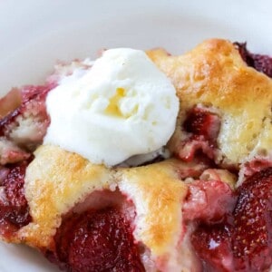 A bowl of strawberry cobbler topped with vanilla ice cream.