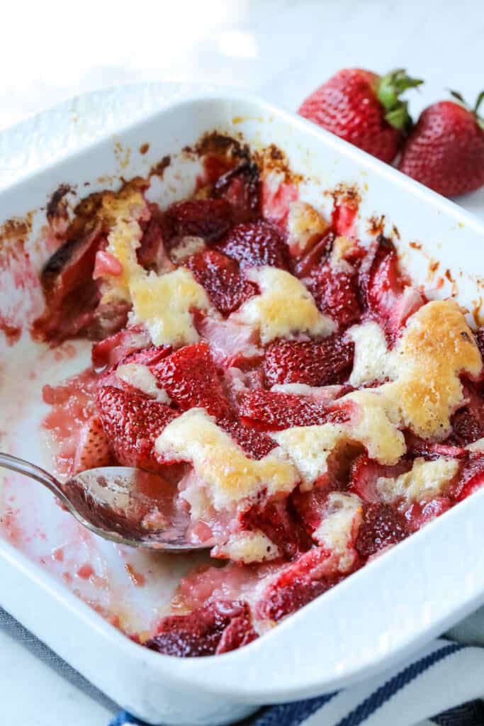 strawberry cobbler being dished out of a white dish. 