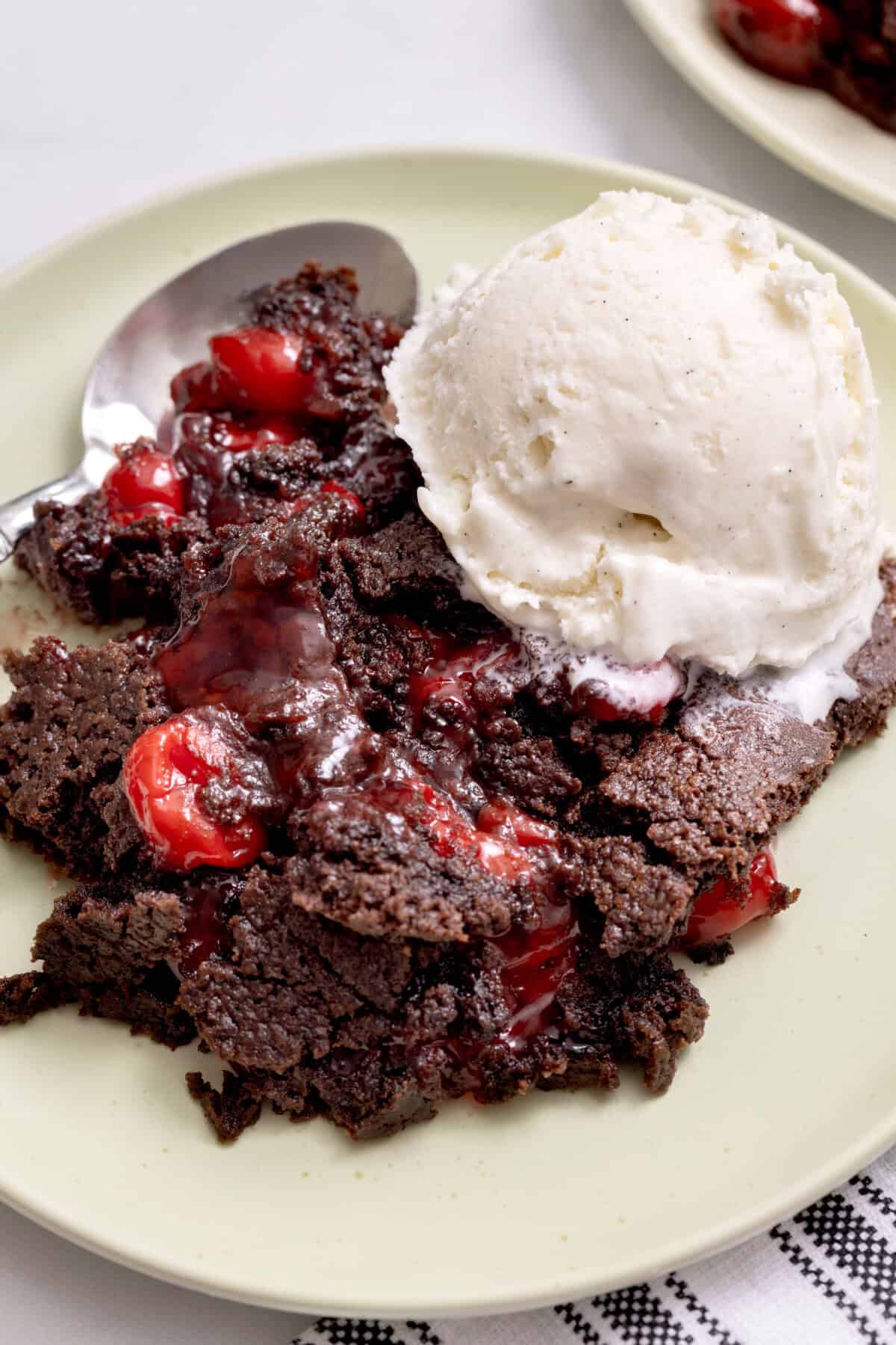 Chocolate cherry dump cake in bowl with scoop of ice cream.