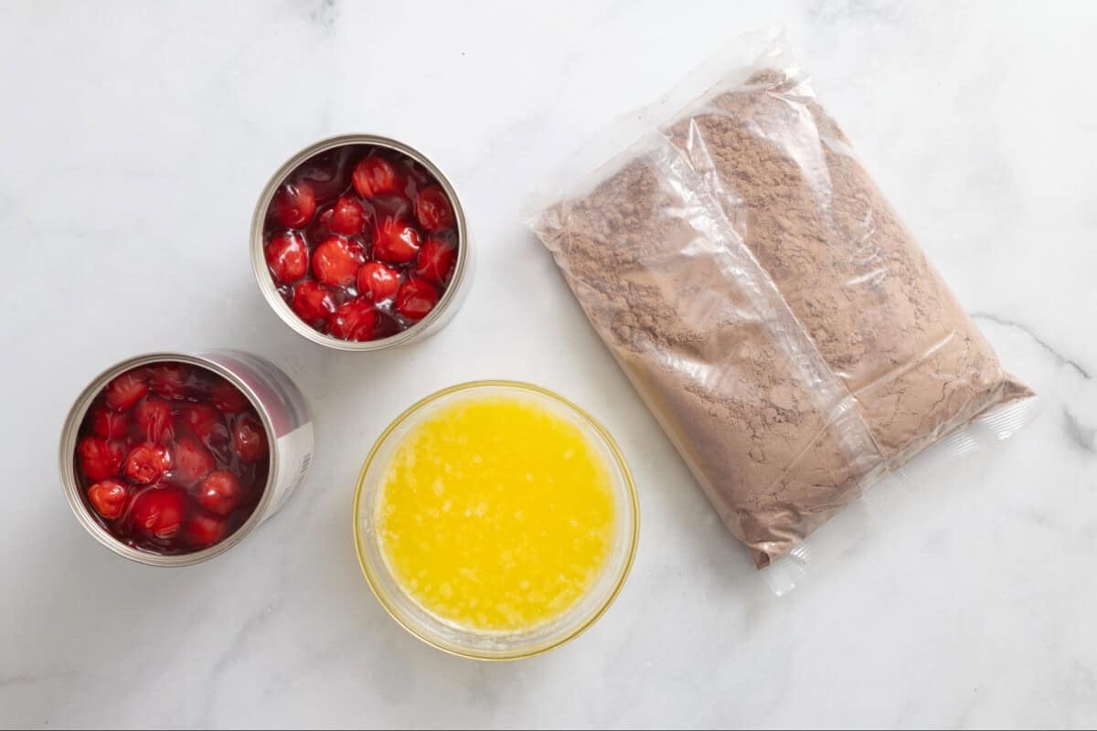 Ingredients for chocolate cherry dump cake, including cake mix, melted butter, and cherry pie filling.