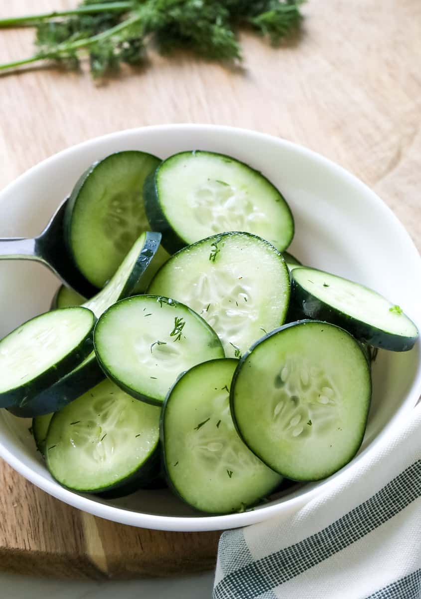 cucumber salad in a white bowl on a wooden background