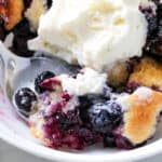 putting ice cream on top of baked blueberry dessert