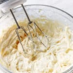 Bowl of cream cheese frosting with hand mixer.