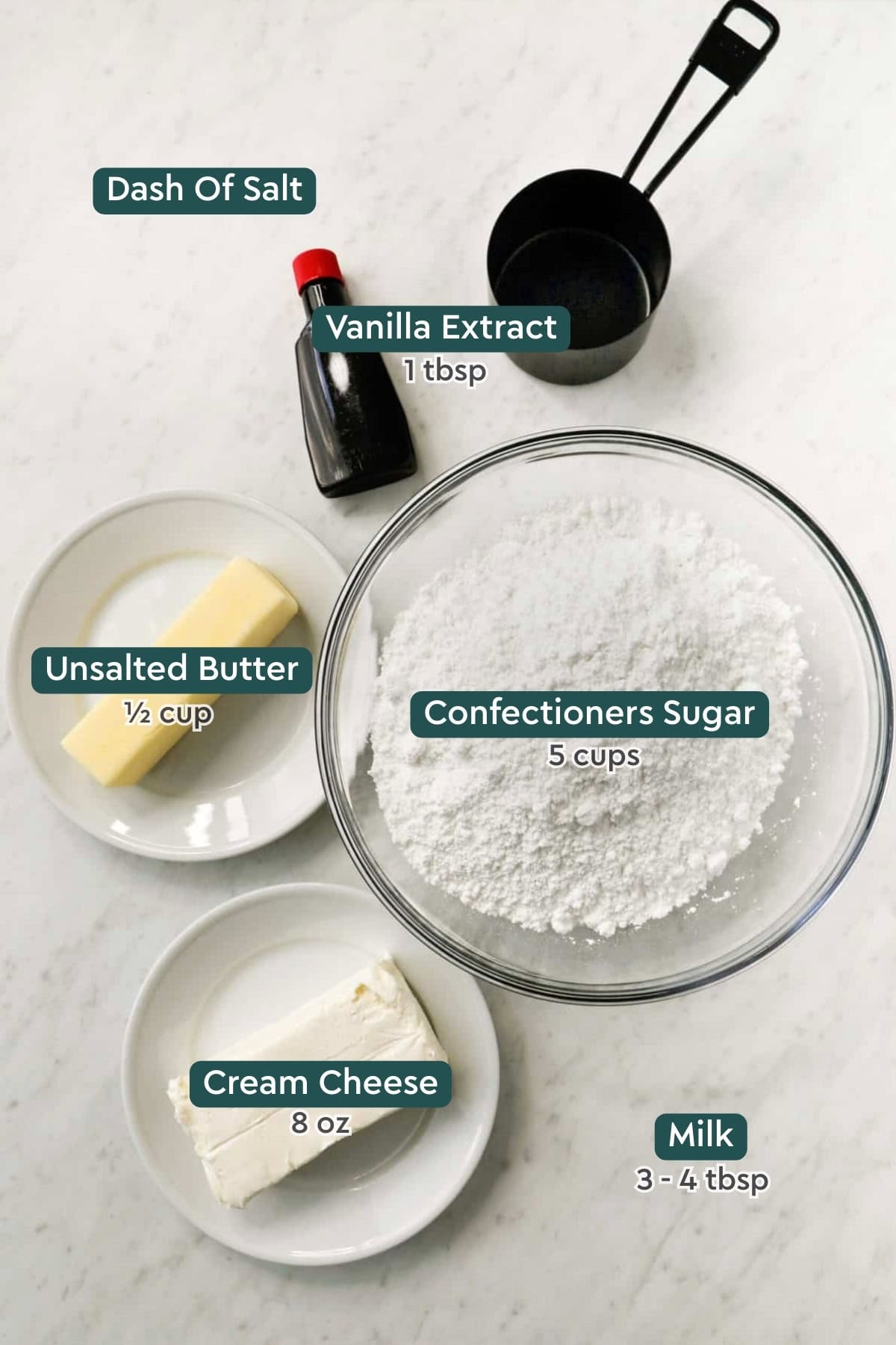 all of the ingredient for cream cheese frosting in bowls on a white countertop