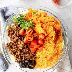 ingredients for doritos taco salad served in a glass round bowl