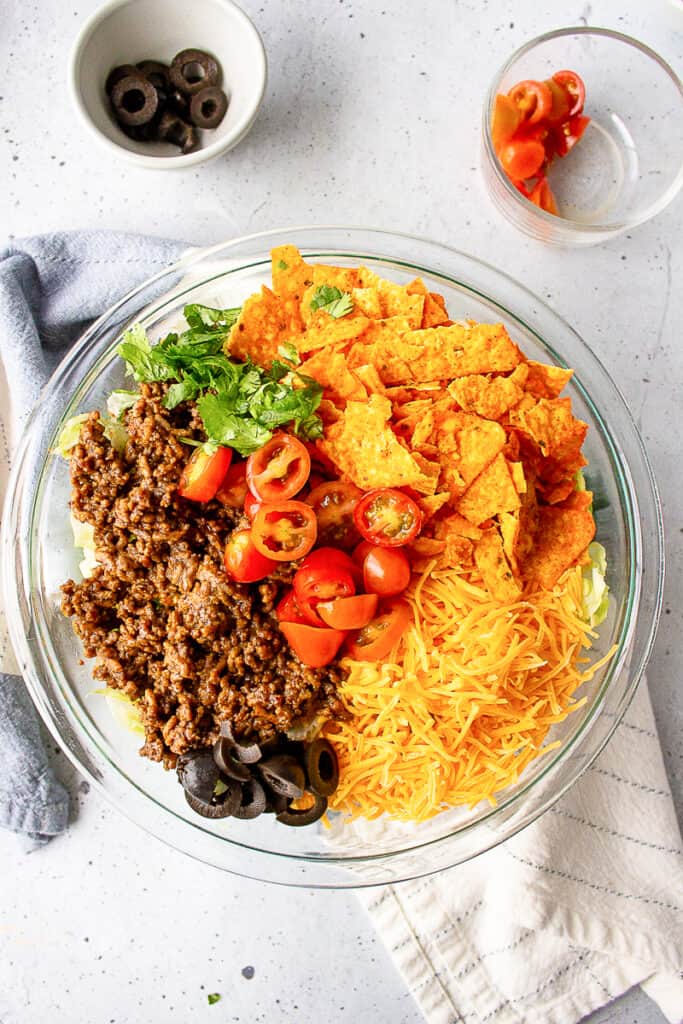 ingredients for doritos taco salad served in a glass round bowl