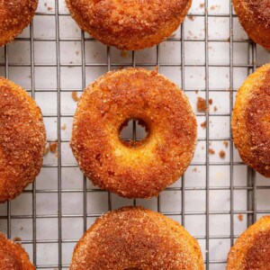 baked apple cider donuts sitting on a metal cooling rack.