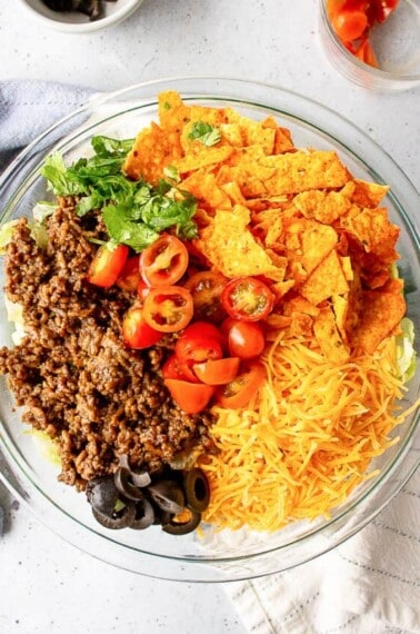 ingredients for doritos taco salad served in a glass round bowl
