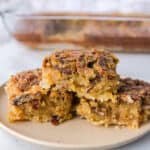 stack of three pecan pie bars served on a tan plate