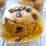A pumpkin chocolate chip muffin on top of a paper liner.