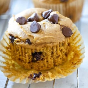 A pumpkin chocolate chip muffin on top of a paper liner.