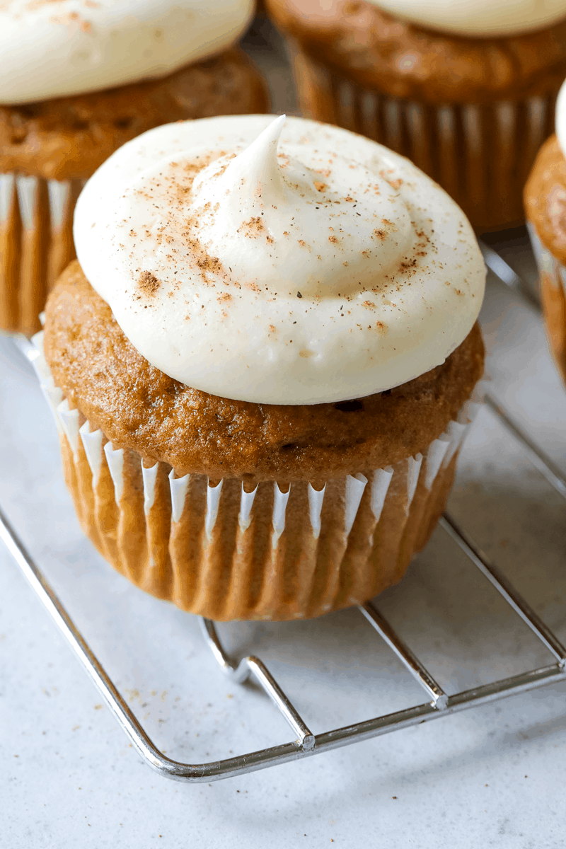 pumpkin spice cupcake with cream cheese frosting on a wire metal cooling rack