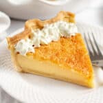 slice of buttermilk pie with whipped cream served on a white plate