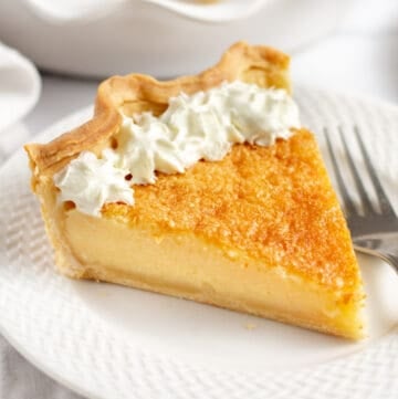 slice of buttermilk pie with whipped cream served on a white plate
