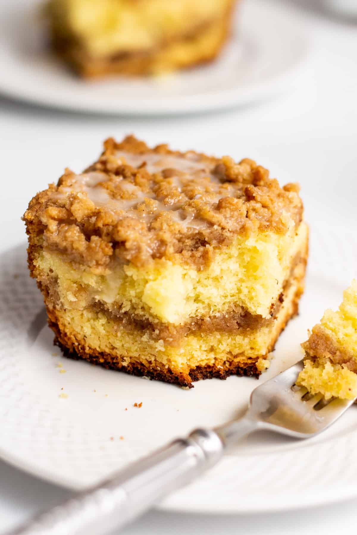 serving of cake mix sour cream coffee cake on a white plate with a forkful of the cake next to it