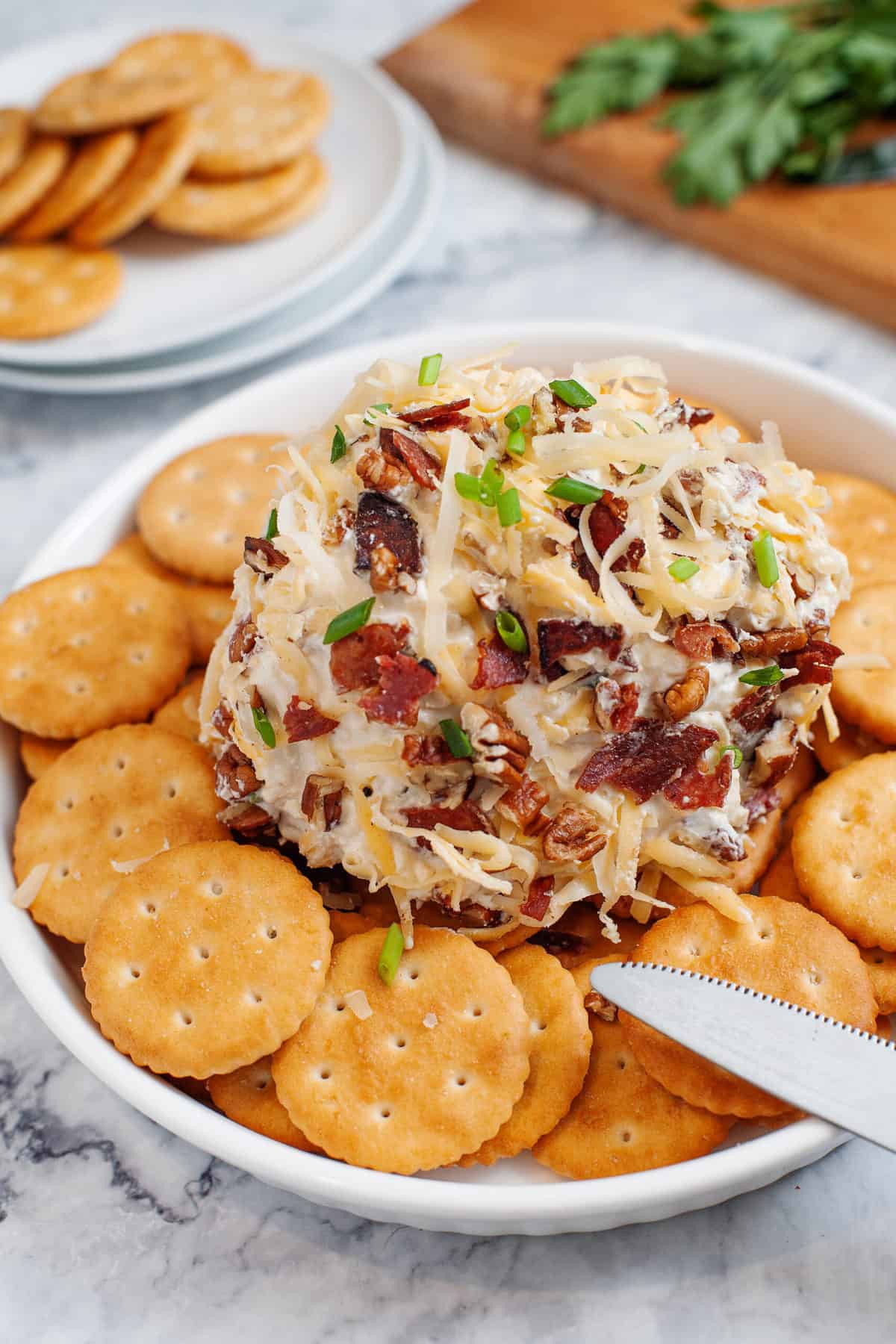 cheese ball served on top of a bed of ritz crackers in a white shallow bowl
