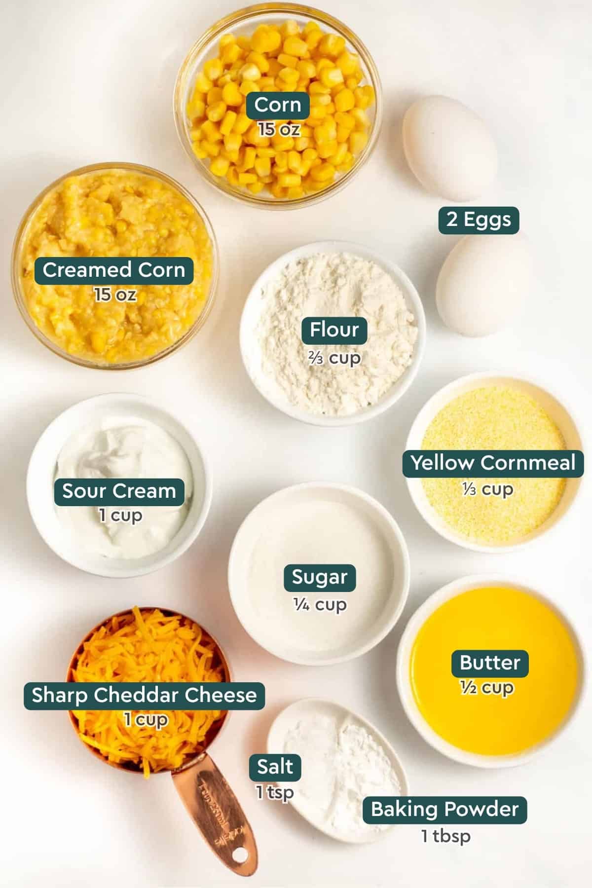 Ingredients for cheesy cornbread casserole: corn, eggs, creamed corn, flour, cornmeal, sour cream, sugar, butter, cheese, salt, baking powder.