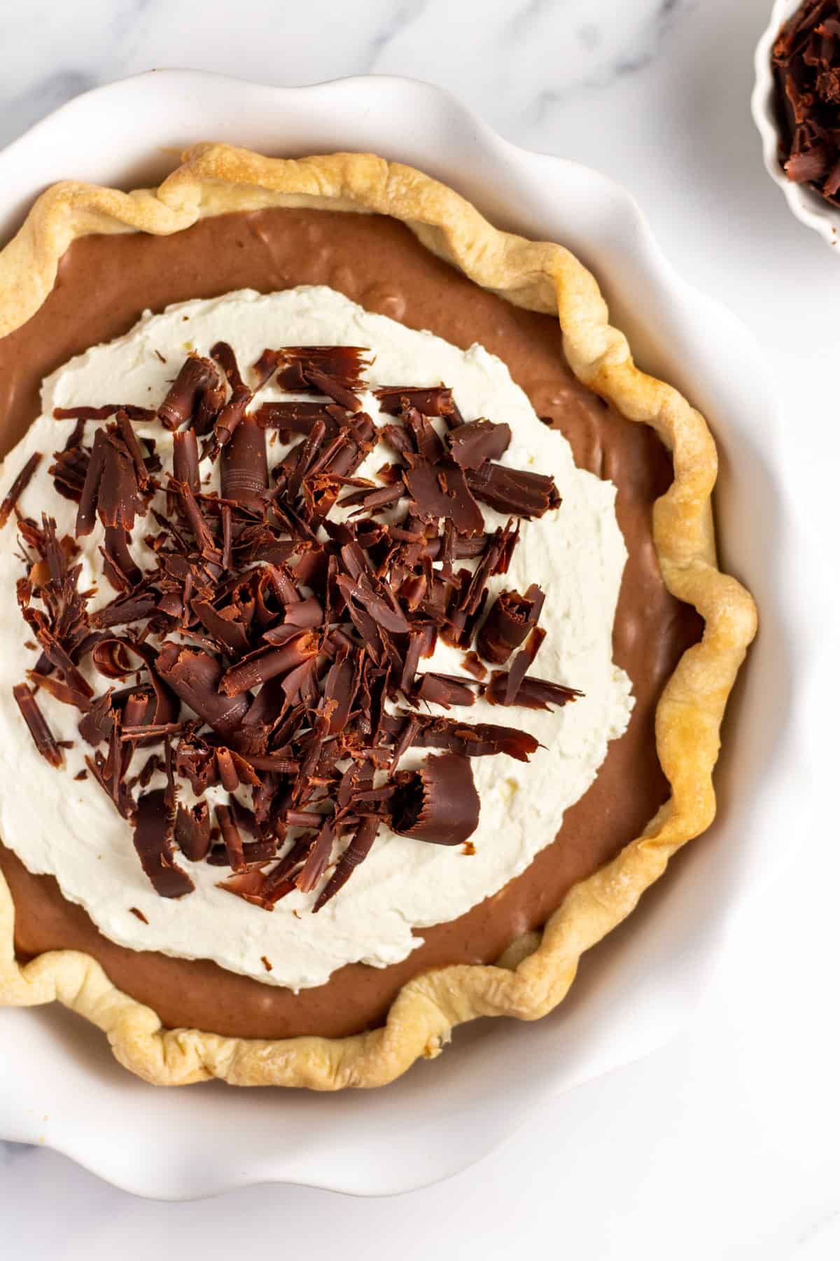 french silk pie with homemade pie crust whipped cream and chocolate shavings served in a pie dish