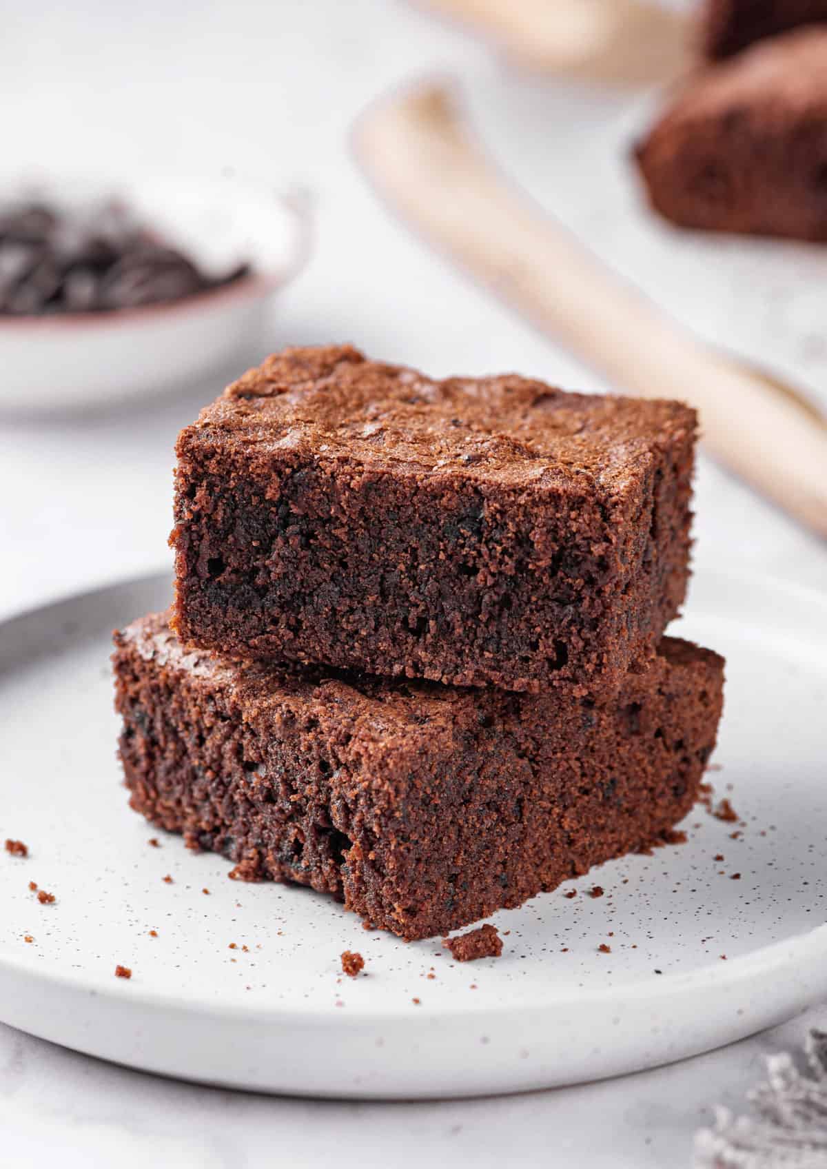 two square servings of fudgy homemade brownies on a white speckled plate